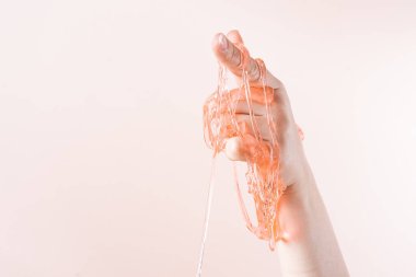 Slime flows down the index finger of the womans hand on a light beige background