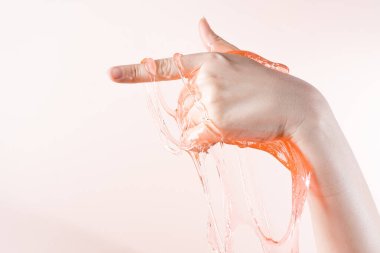 Slime flows down the index finger of the womans hand on a light beige background