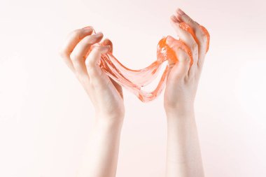 Stretching on the fingers of the slime. Honey flows down on a beige background