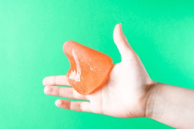 Liquid wax flows down the finger of the womans hand on a green background