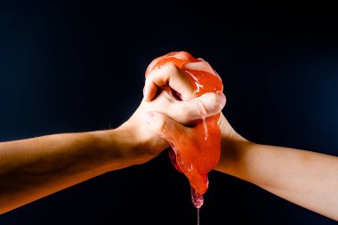 Erkekler ve kadınların elleri siyah arka planda balçığı sıkıştırır