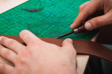 Deri ustası kemerin kenarlarını boş tutar.