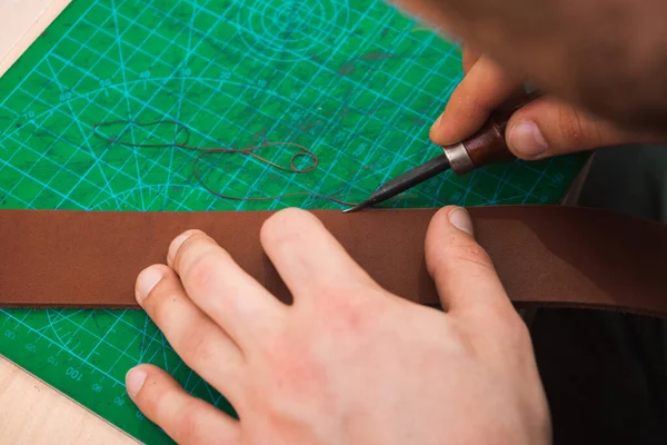 Deri ustası kemerin kenarlarını boş tutar.