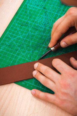 Deri ustası kemerin kenarlarını boş tutar.