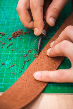 Deri ustası kemerin kenarlarını boş tutar.