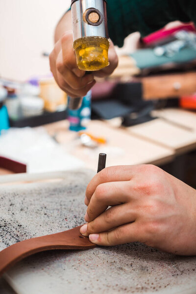 Hammer hits the chisel to make a leather belt