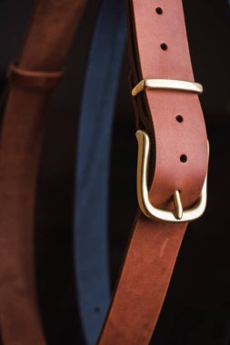 Siyah arka planda altın tokalı mavi ve kahverengi deri kemer büyük bir plan.