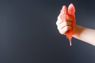 Sümük kadınların işaret parmağından aşağı akar. Gri arka planda bir el.