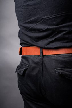 Siyah takım elbiseli bir adamın belinde kırmızı deri kemer.