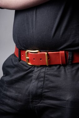 Siyah takım elbiseli bir adamın belinde kırmızı deri kemer.