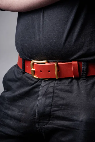 Siyah takım elbiseli bir adamın belinde kırmızı deri kemer.