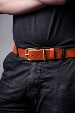 Siyah takım elbiseli bir adamın belinde kırmızı deri kemer.