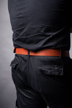 Siyah takım elbiseli bir adamın belinde kırmızı deri kemer.