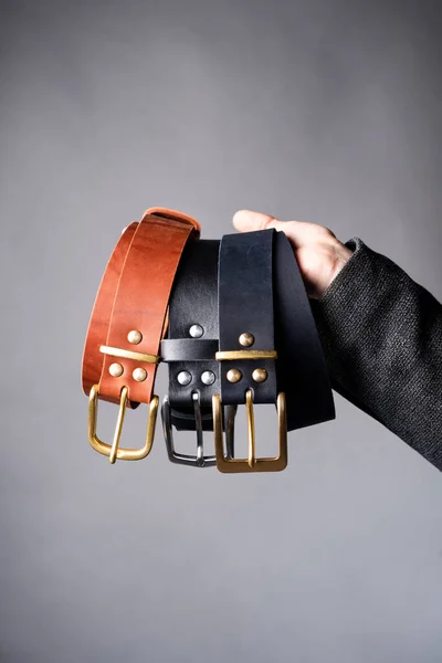 Leather straps in hand on a gray background