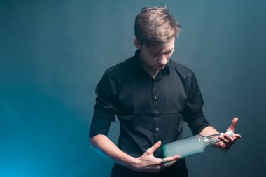 Genç bir adam elinde dumanla dolu bir şişe tutuyor.