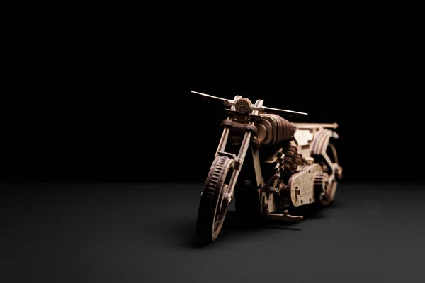 Toy motorcycle made of plywood on a black background