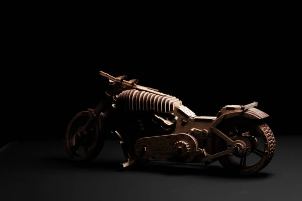 Motocicleta de brinquedo feita de madeira compensada em um fundo preto — Fotografia de Stock