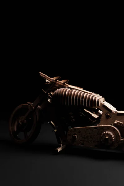 Wooden toy-motorcycle designer on a black background — Stock Photo, Image