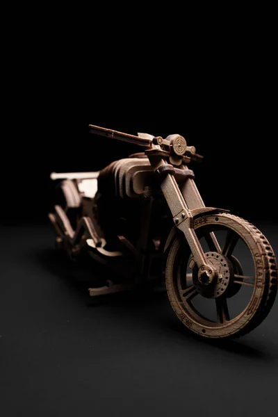 Деревянный игрушечный мотоцикл на черном фоне крупный план — стоковое фото