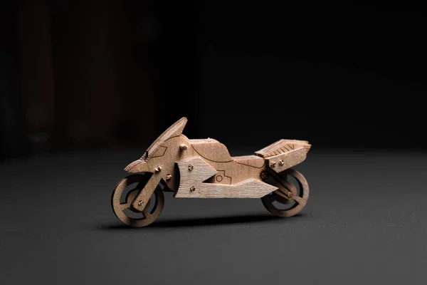 Toy motorcycle made of plywood on a black background