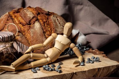 Çizim yapmak için kullanılan manken tahtanın üzerinde, ekmeğin yanında ve kahverengi arka planda bir kavanoz bisküvi var.