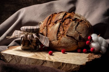 Ekmek ve bir kavanoz bisküvi kahverengi arka planda tahta bir tahta üzerinde duruyor.