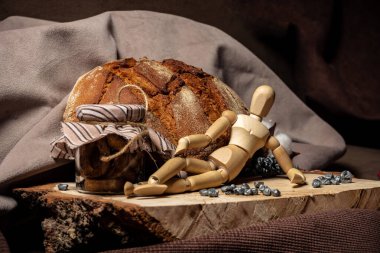 Çizim yapmak için kullanılan manken tahtanın üzerinde, ekmeğin yanında ve kahverengi arka planda bir kavanoz bisküvi var.