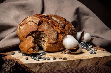 Bir parça ısırılmış ekmek, ahşap arka planda bir somun ekmeğin yanında.