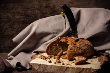 Kahverengi bir arka planda tahta bir stantta ekmeğe saplanmış bıçak.