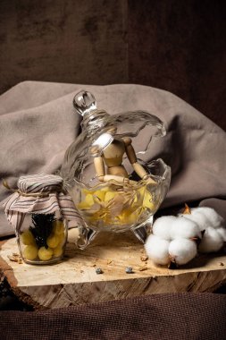 Resim yapmak için kullanılan manken, bej arka planda sarı tatlılar bulunan bir kavanozun yanında şekerle birlikte bir vazoda yatıyor.