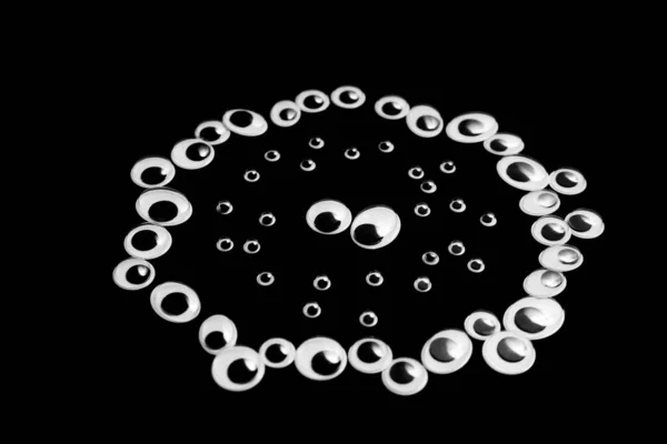 Un círculo de ojos de juguete. llena de pequeños ojos sobre un fondo negro — Foto de Stock