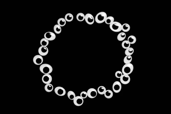 Um círculo de olhos de brinquedo em um fundo preto — Fotografia de Stock