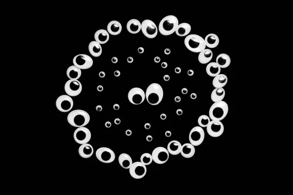 Um círculo de olhos de brinquedo. preenchido com pequenos olhos em um fundo preto — Fotografia de Stock