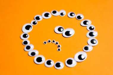 Turuncu arka planda oyuncak gözlerden duygusal gülen yüz