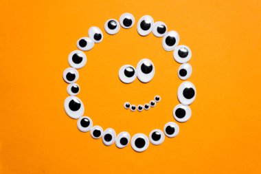 Tek renkli turuncu arka planda oyuncak gözlerle gülümse.