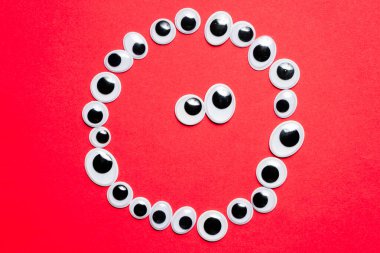 Tek renkli kırmızı bir arka planda oyuncak gözlerle gülümsemek.