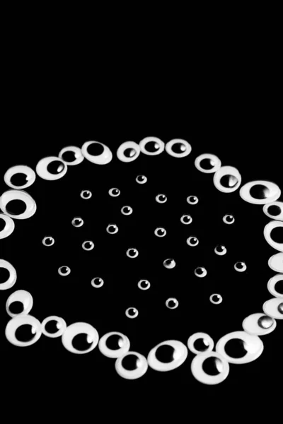 A circle of toy eyes on a black background — Stock Photo, Image