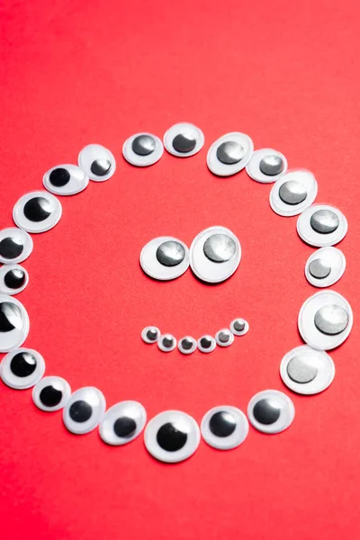 Tek renkli kırmızı bir arka planda oyuncak gözlerle gülümsemek.