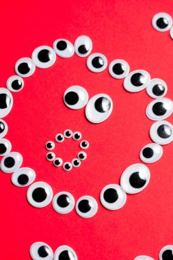 Kırmızı arka plandaki oyuncak gözlerden duygusal gülen yüz