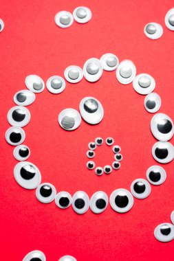 Kırmızı arka plandaki diğer gözlerin etrafındaki oyuncak gözlerden gelen şaşkın gülen yüz.