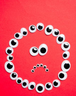 Kırmızı arka plandaki oyuncak gözlerden duygusal gülen yüz