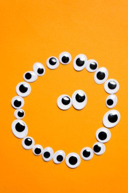 Tek renkli turuncu arka planda oyuncak gözlerle gülümse.