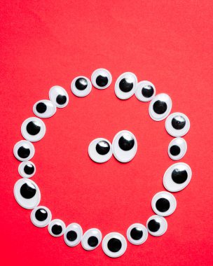 Tek renkli kırmızı bir arka planda oyuncak gözlerle gülümsemek.