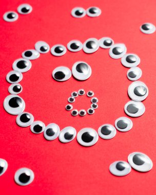 Kırmızı arka plandaki diğer gözlerin etrafındaki oyuncak gözlerden gelen şaşkın gülen yüz.