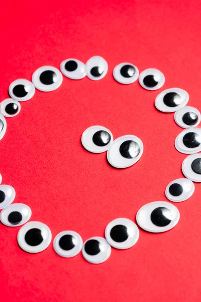 Tek renkli kırmızı bir arka planda oyuncak gözlerle gülümsemek.