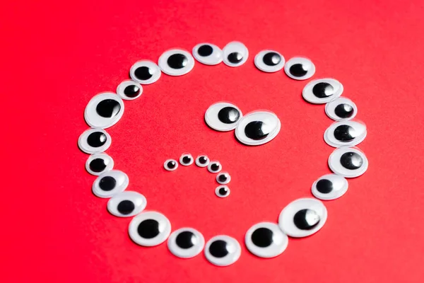 Kırmızı arka plandaki oyuncak gözlerden duygusal gülen yüz