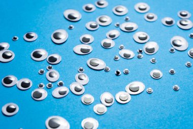 Farklı boyutlarda oyuncak gözler mavi arka plana saçılmış.