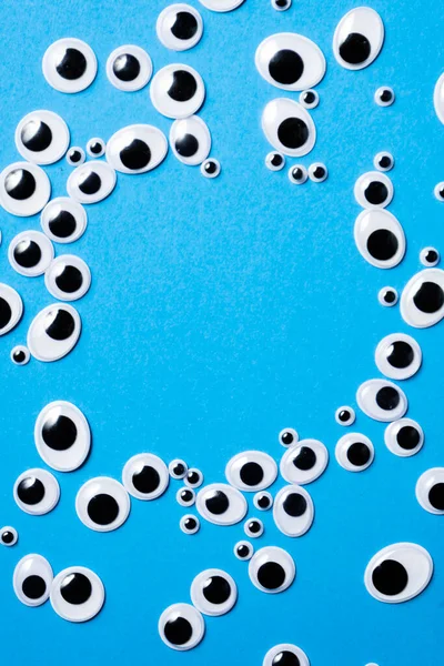 青い背景に散在するさまざまなサイズのおもちゃの目 — ストック写真