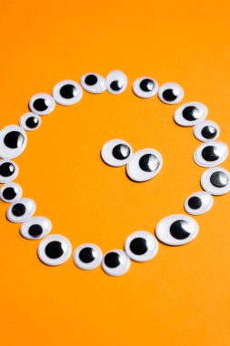 Tek renkli turuncu arka planda oyuncak gözlerle gülümse.