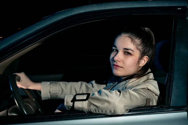 A rapariga ao volante do carro olha pela janela — Fotografia de Stock